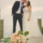 Lina and Matt kissing on the dock. Bouquet in focus up close.