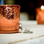 Wedding rings next to a candle.