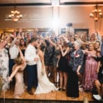 Haley & Matt kissing on the dance floor with the wedding party and guests.